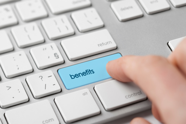 Computer keyboard with a finger hovering over the shift button that has been modified to read "benefits"