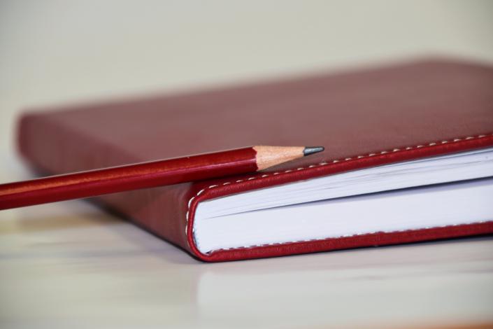 red notebook and pencil